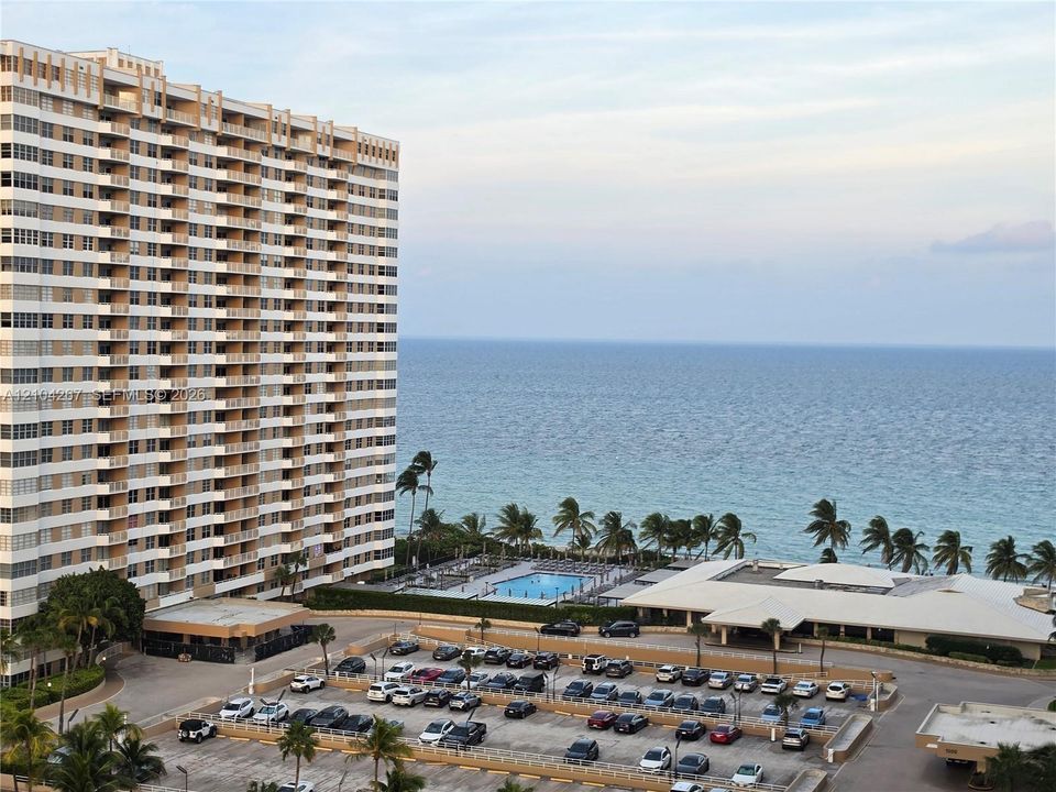 High-rise building featuring private balconies, an on-site swimming pool, and dedicated parking, situated along the coastline