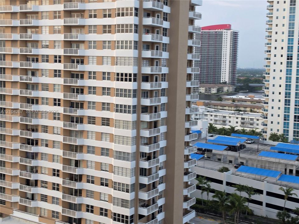 High-rise residential tower exterior featuring tiered balconies with metal railings and multi-pane window configurations