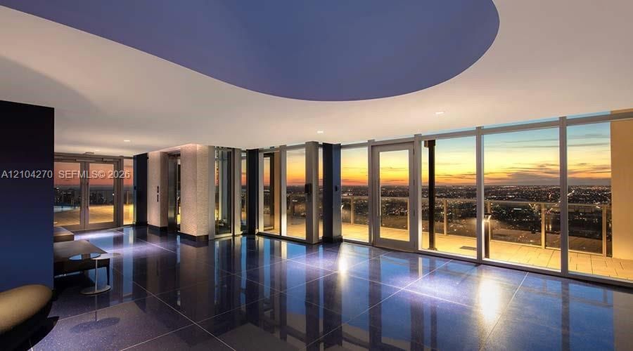 Floor-to-ceiling glass walls, polished stone flooring, recessed ceiling lighting, and a wrap-around exterior terrace