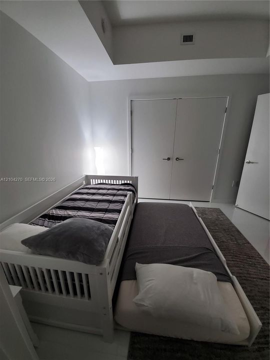 Room featuring a tray ceiling, smooth-finish flooring, and a double-door closet with metallic hardware