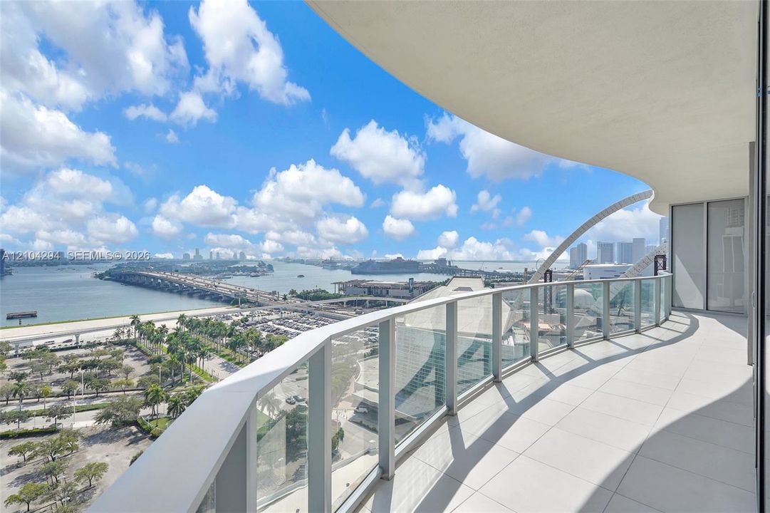 Expansive balcony with glass panel railings and a curved overhead architectural element