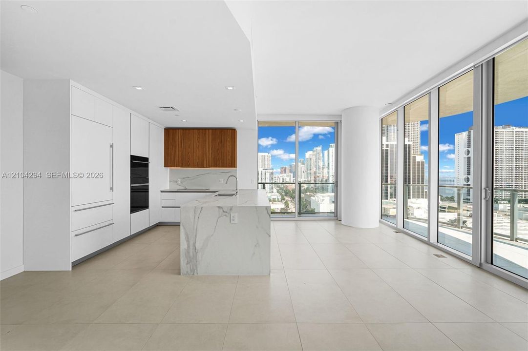 Open-concept kitchen with a waterfall island, integrated appliances, and wood-finish cabinetry