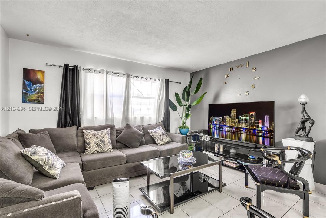 Living area featuring neutral tile flooring, a dark gray accent wall, and horizontal window configuration