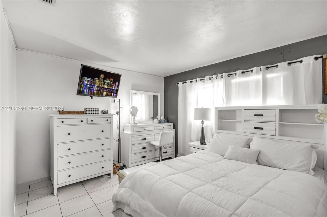 Room featuring light-colored tile flooring, a dual-tone wall finish, and an integrated curtain rod system