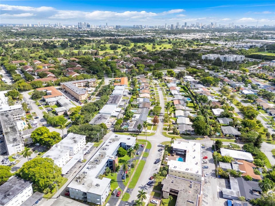 Aerial perspective of the residential grounds featuring mature shade trees, paved walkways, and multiple swimming pools