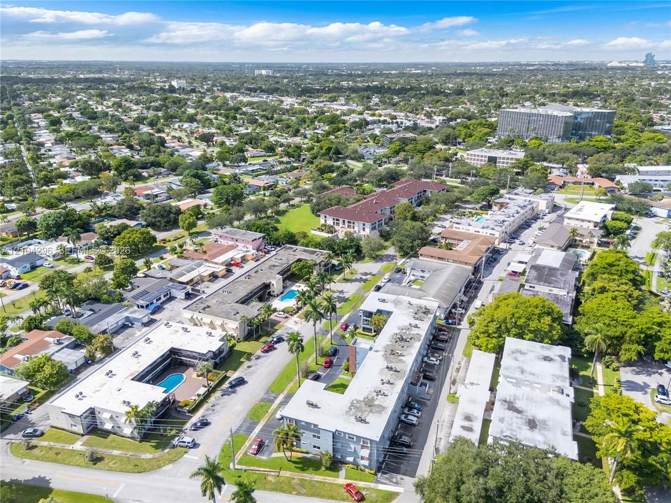 Aerial perspective of a multi-unit residential complex featuring flat-roof structures, dedicated parking areas, and a communal swimming pool