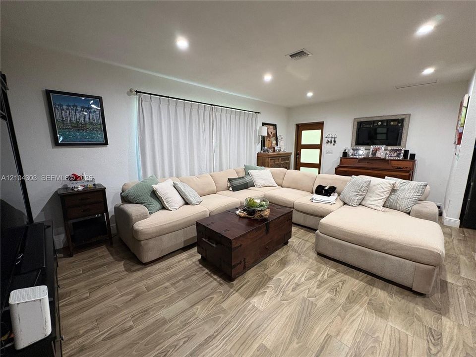 Living area featuring wood-finish flooring, recessed lighting, and a multi-pane glass entry door