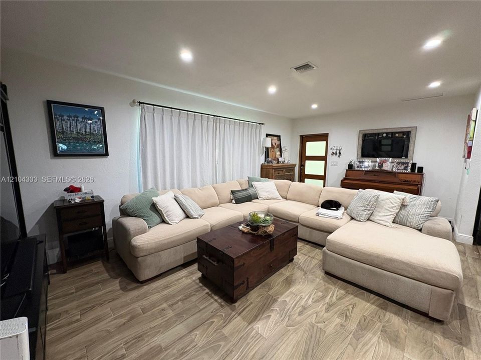 Living area featuring wood-finish flooring, recessed lighting, and a multi-panel exterior entry door with glass inserts