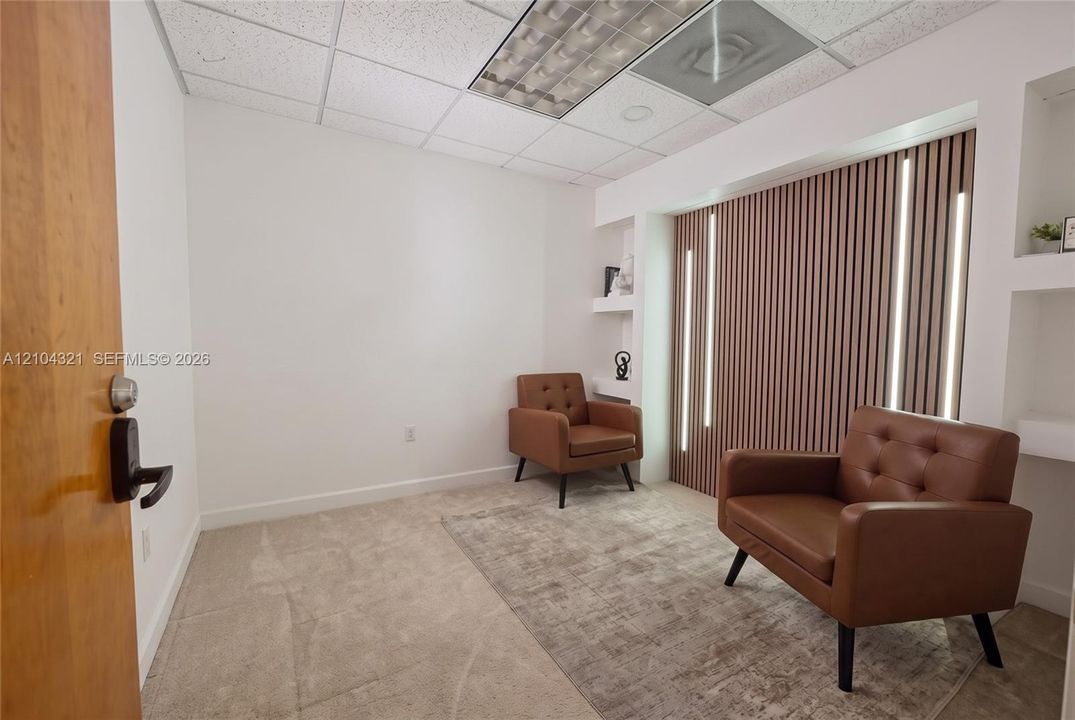 Room featuring a vertical wood-slat accent wall with integrated LED lighting, recessed display shelving, and neutral carpeting
