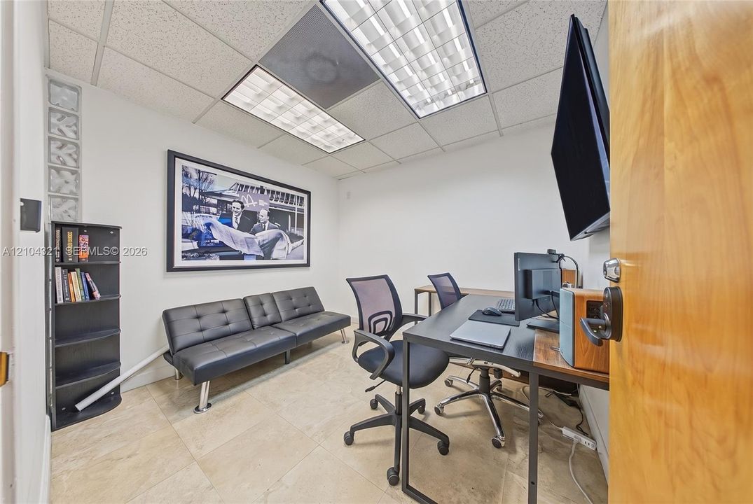 Office space featuring tile flooring, a glass block accent panel, and recessed fluorescent lighting