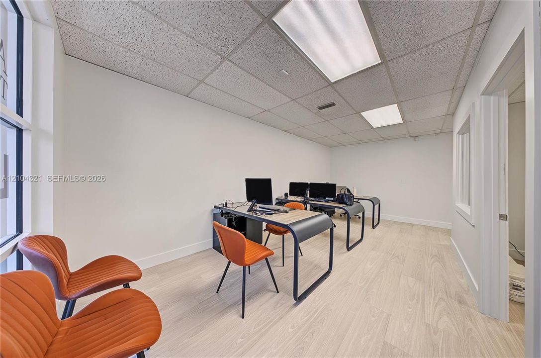 Wood-finish flooring, drop ceiling with integrated rectangular lighting, and large pane window