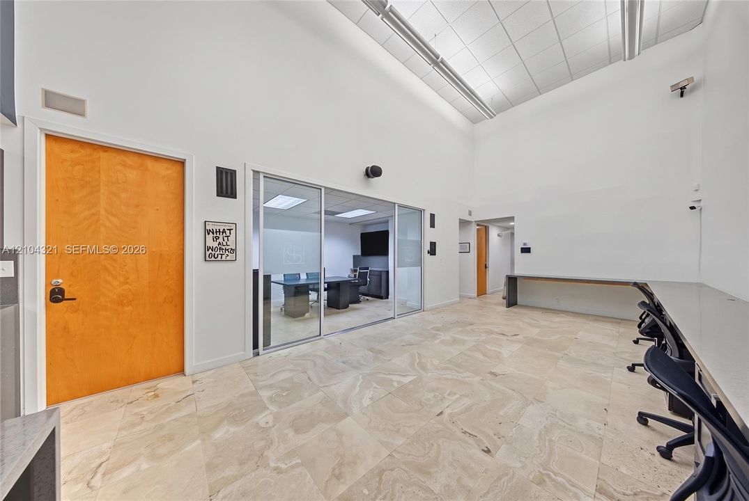 Vaulted ceilings featuring recessed lighting, stone-finish flooring, built-in wall-mounted desk, and glass-paneled interior partition