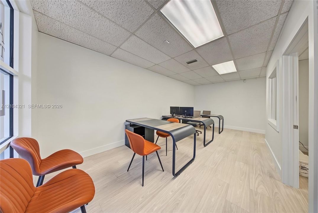 Interior space featuring light-toned wood-finish flooring, drop-ceiling panels, and recessed fluorescent lighting