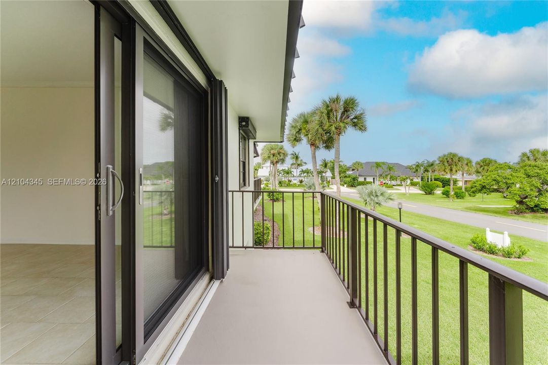 Covered balcony featuring metal railing, sliding glass doors, and light-toned flooring