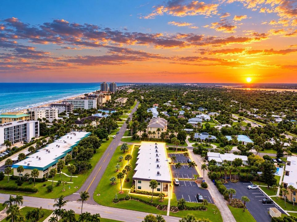 Aerial perspective of the coastal property featuring paved on-site parking, exterior lighting, and immediate proximity to the shoreline