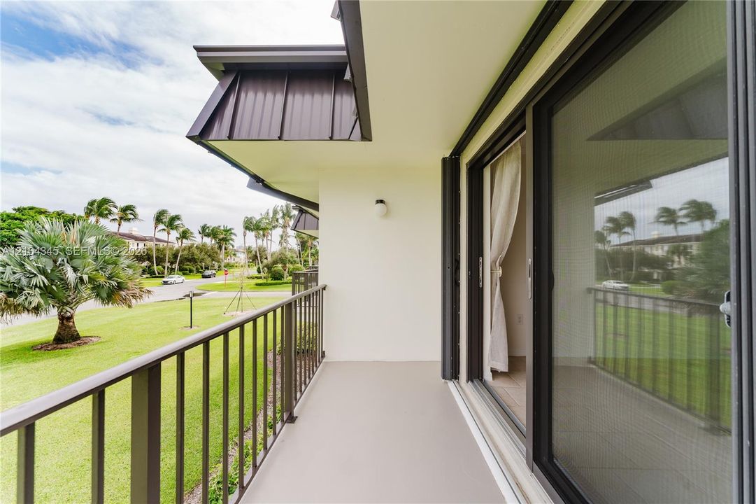 Covered balcony featuring dark metal railings, metal roof accents, and sliding glass entry doors