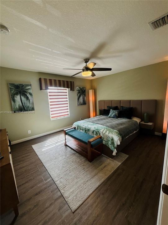 Wood-finish flooring, two six-panel interior doors, and a circular flush-mount ceiling light fixture with integrated fan