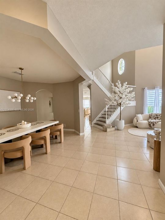 Built-in white cabinetry with brushed nickel hardware, neutral solid-surface countertop, decorative geometric tile backsplash, and arched architectural entryways