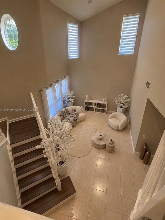 Spacious room featuring wood-finish flooring, recessed tray ceiling, ceiling fan, and decorative vertical slat wall panels with integrated lighting