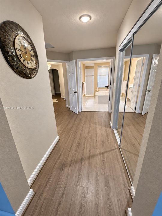 Vertical wood-slat accent wall with integrated gold metallic inlays, wood-finish flooring, tray ceiling, and arched entryway