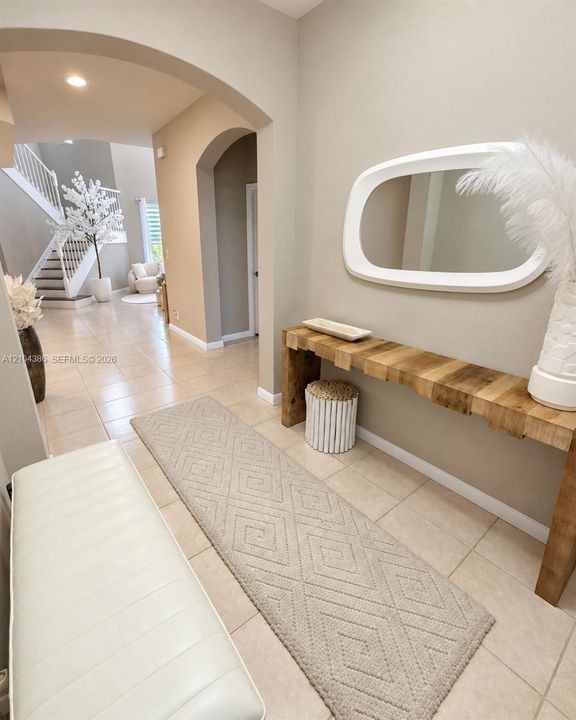 Vaulted ceilings featuring custom oval accent windows, tiered vertical windows, and neutral tile flooring