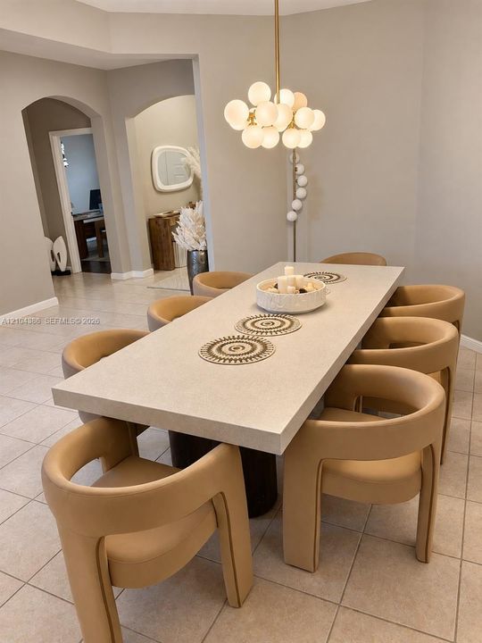 Kitchen featuring white cabinetry, solid-surface countertops, center island, integrated stainless steel sink with gooseneck faucet, and tile flooring