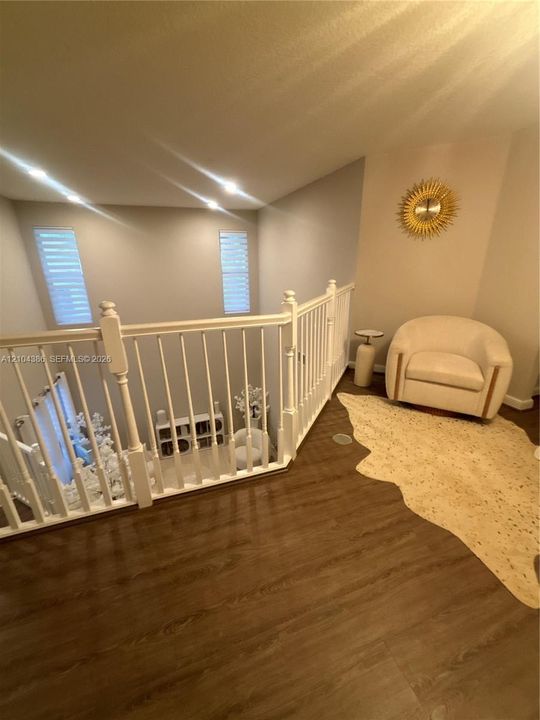 Tray ceiling featuring a central ceiling fan, wood-finish flooring, and a textured dark wood accent wall
