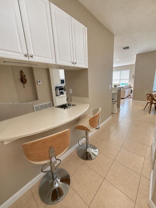Living area featuring vertical slat wood-finish accent wall, large format tile flooring, recessed ceiling lighting, brushed nickel ceiling fan, and multi-pane horizontal windows with installed roller shades