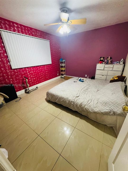 Large-format ceramic tile flooring, ceiling fan with integrated lighting, and window blinds