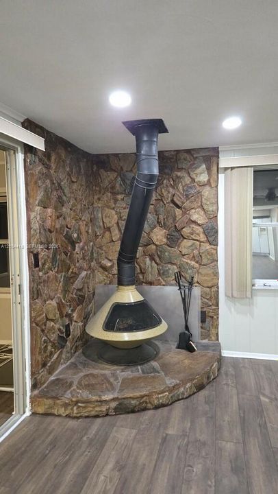 Mid-century modern cone fireplace set upon a raised, irregularly shaped natural stone hearth, complemented by a floor-to-ceiling natural stone wall and recessed lighting
