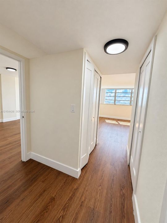 Wood-finish flooring, multi-panel closet doors, and flush-mount circular lighting fixtures