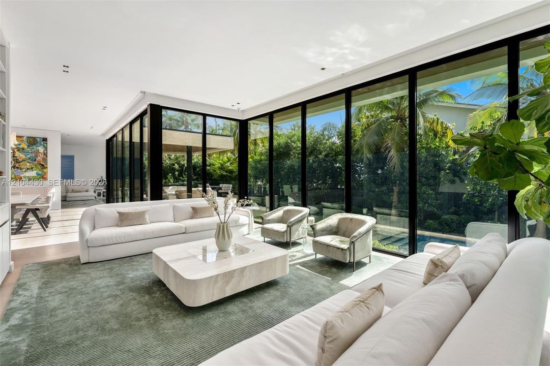 Living area featuring expansive floor-to-ceiling black-framed glass walls, recessed ceiling lighting, and built-in shelving