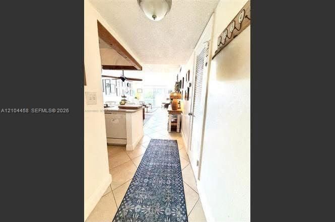 Interior hallway featuring diagonal ceramic tile flooring, a semi-flush mount ceiling fixture, and a louvered closet door