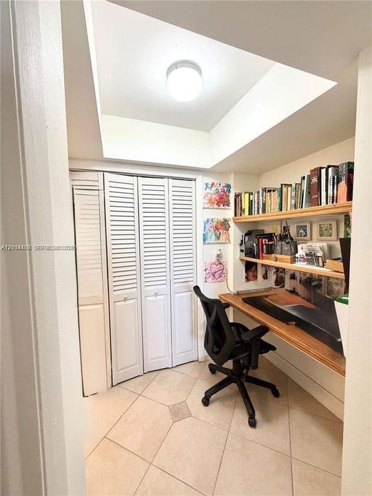 Built-in wooden desk, integrated shelving, louvered bi-fold closet doors, tile flooring, and recessed ceiling lighting