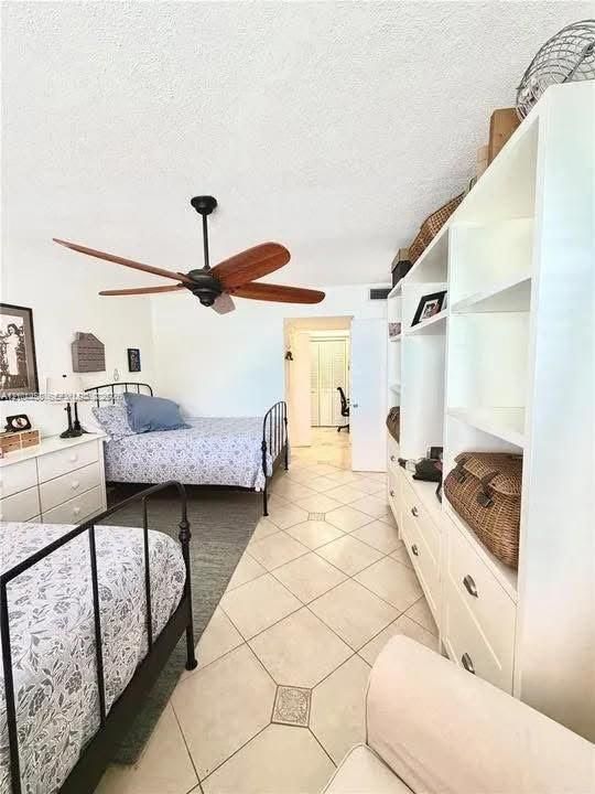 Spacious room featuring diagonal tile flooring, custom white built-in cabinetry, and a ceiling fan with wood-finish blades