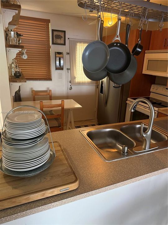 Kitchen featuring a dual-basin stainless steel sink, pull-down faucet, solid-surface countertops, and ceiling-mounted cookware rack
