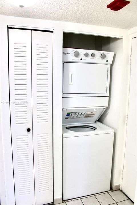 Stackable laundry unit featuring a white finish and louvered bi-fold closet doors