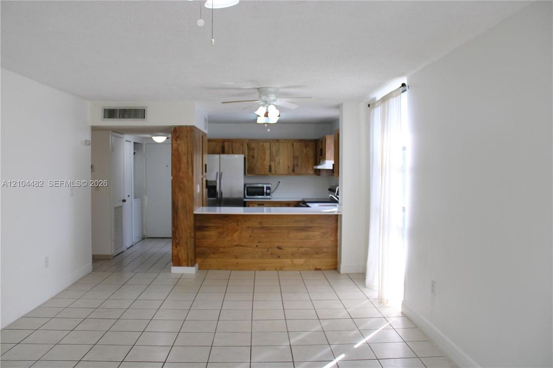 Kitchen featuring wood-finish cabinetry, white solid-surface countertops, a breakfast bar, and stainless steel appliances
