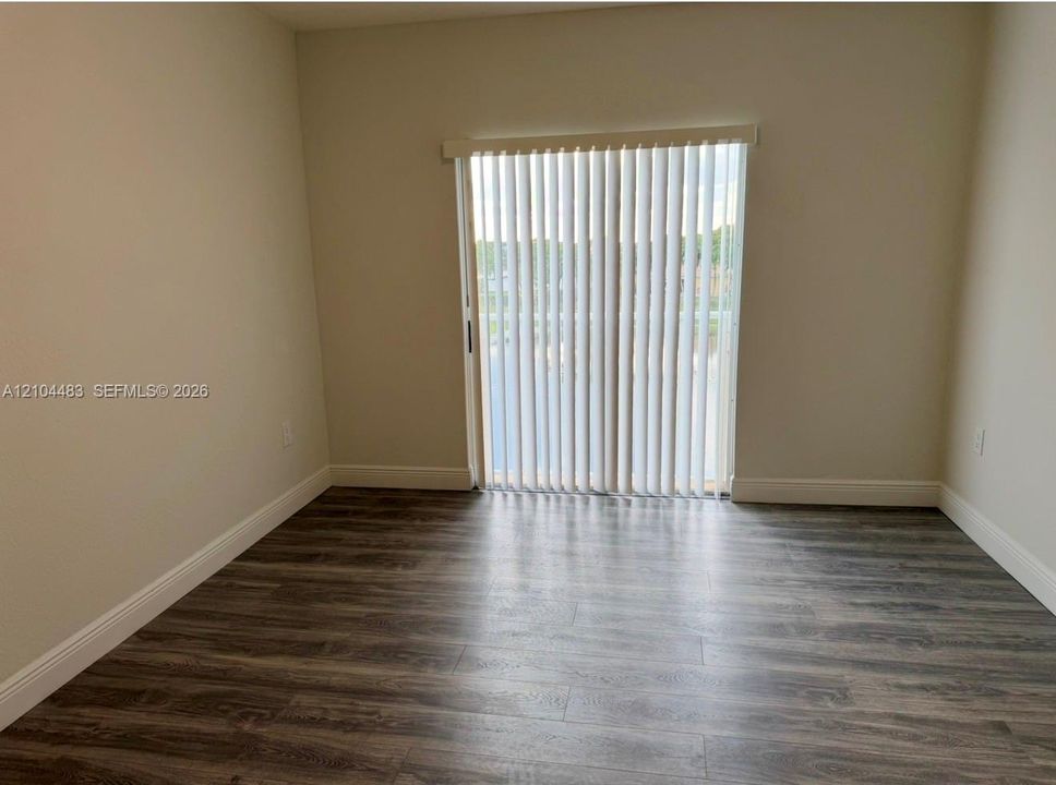 Wood-finish flooring, light-toned walls, and a sliding glass door with vertical blinds