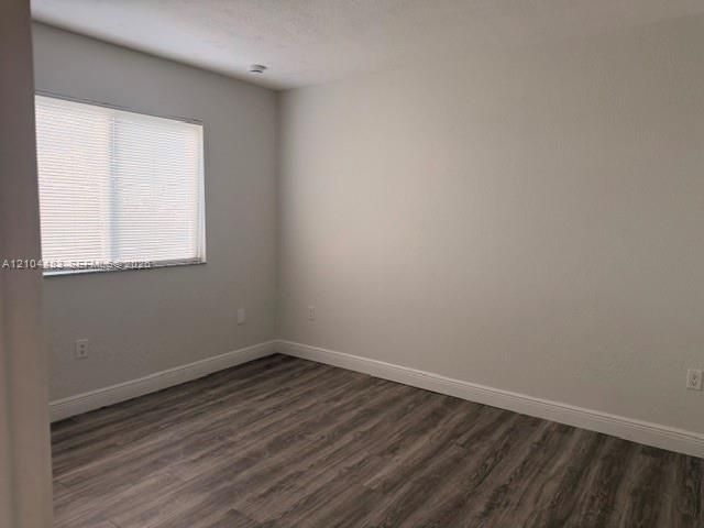Wood-finish flooring, white wall paint, window with blinds, and white trim