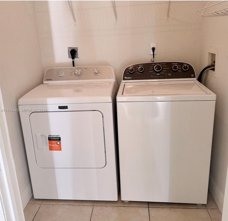 Laundry area with tile flooring and a built-in wire shelf