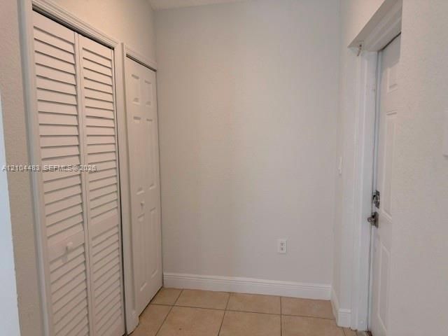 Louvered bi-fold doors, four-panel door, ceramic tile flooring, and wall-mounted electrical outlet