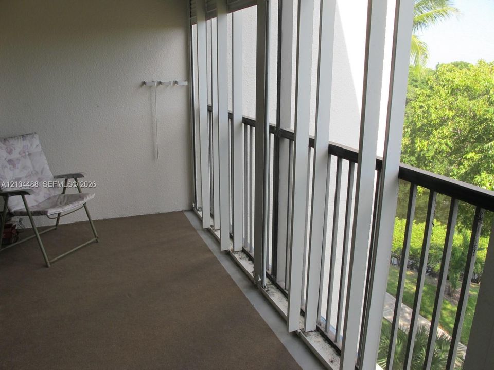 Enclosed balcony with textured wall finish and a dark-colored flooring