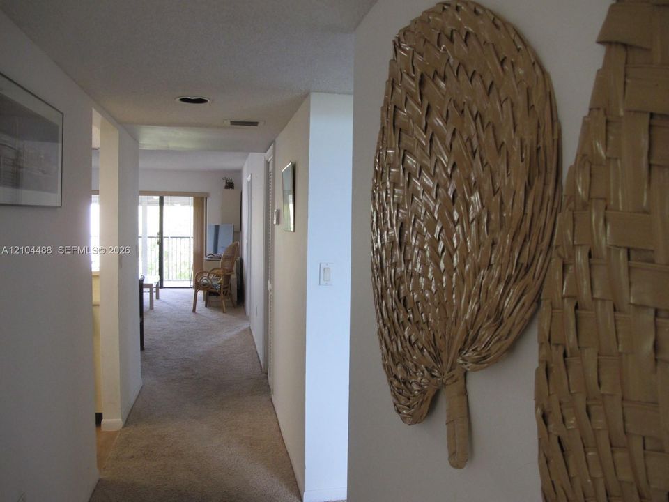 Carpeted hallway leading to a room with a sliding glass door and an exterior balcony