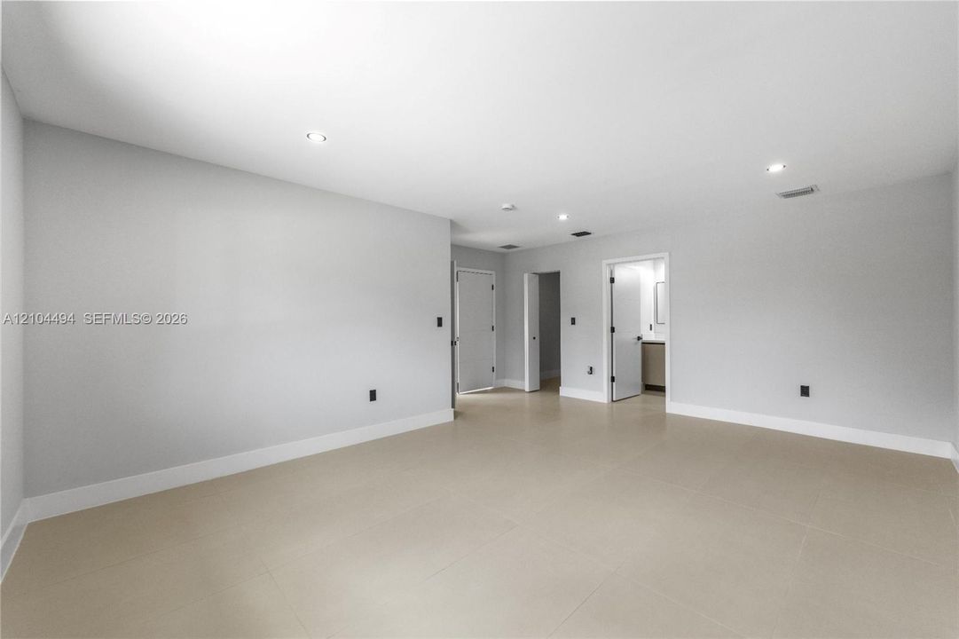 Open interior space featuring neutral wall paint, large-format tile flooring, and recessed ceiling lighting