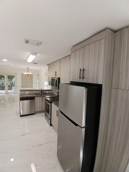 Polished stone-finish tile flooring, glass-paneled double doors, five-arm bronze chandelier, and multi-directional track lighting