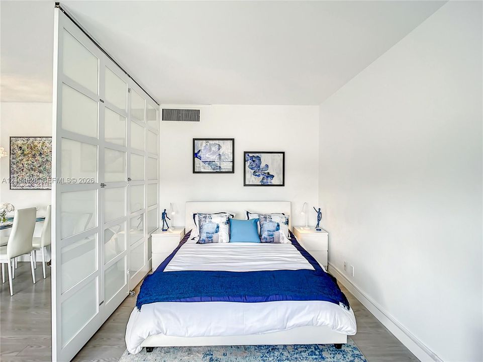 Floor-to-ceiling glass panel room divider with white frames and light-tone wood-finish flooring