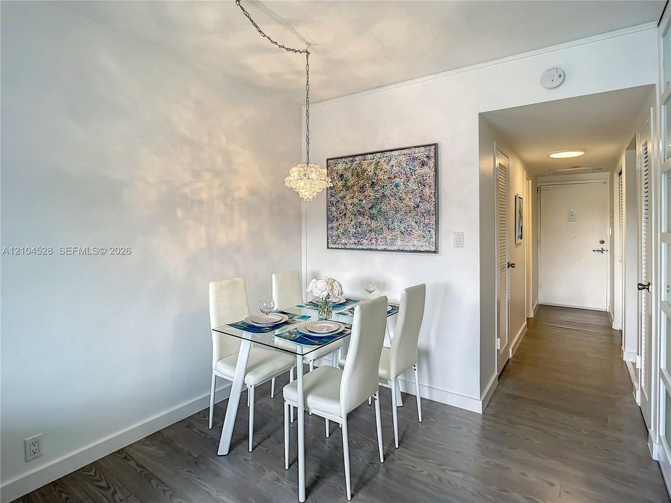 Wood-finish flooring, crisp white walls, and a decorative crystal-style pendant light fixture with a chain suspension