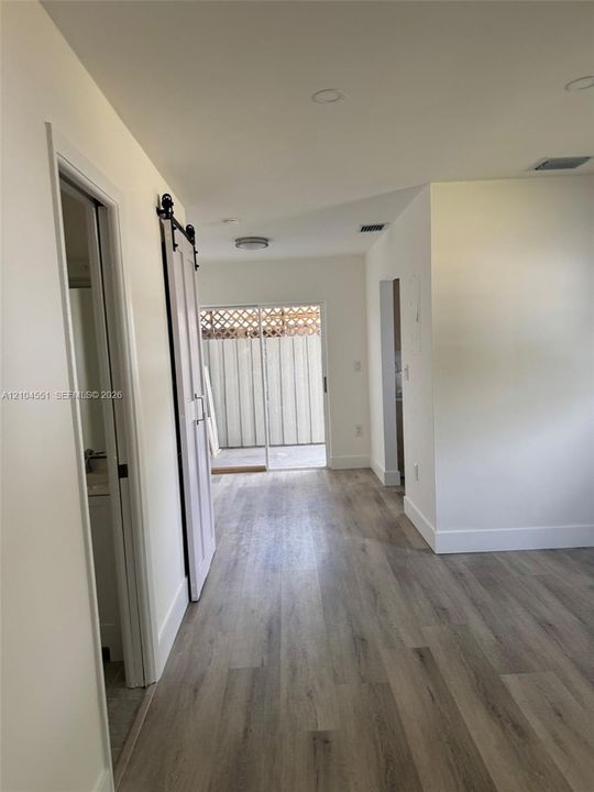 Interior space featuring wood-finish flooring, sliding barn door, recessed lighting, and a sliding glass door providing external access
