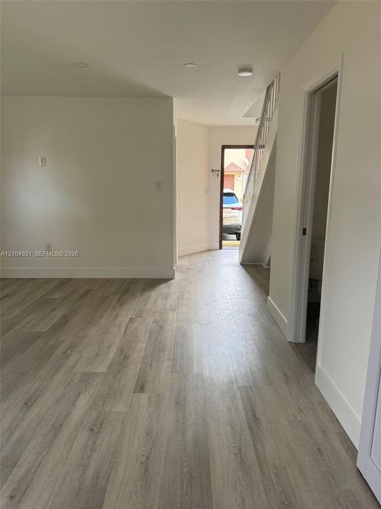 Interior space featuring neutral wall paint, wood-finish flooring, recessed lighting, and a staircase with a white metal railing